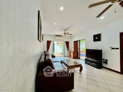 Spacious living room with elegant decor and pool view, featuring comfortable seating and modern entertainment setup.