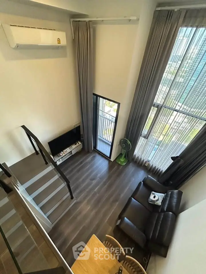 Modern loft-style living room with high ceilings and large windows offering a stunning view.