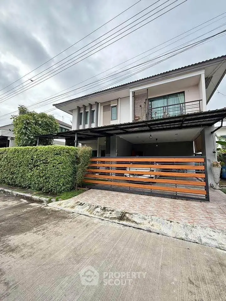 Modern two-story house with balcony and garage in a suburban neighborhood.