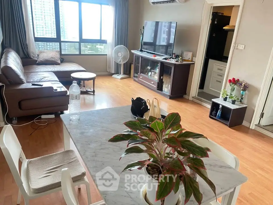 Spacious living room with modern decor and large windows offering city views.