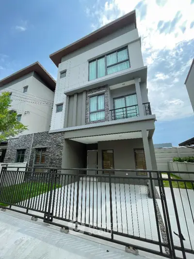 Modern three-story house with sleek design and gated driveway in a serene neighborhood.