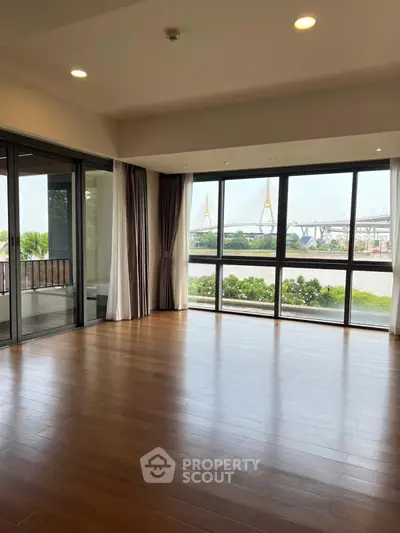 Spacious living room with large windows offering stunning river and bridge views.