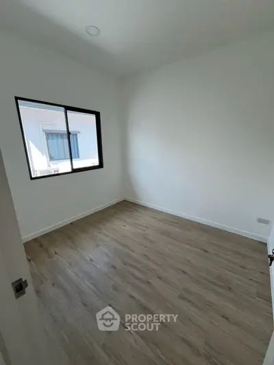 Spacious empty room with wooden flooring and large window