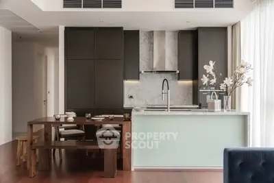 Modern kitchen with sleek cabinetry and elegant dining area, featuring a marble countertop and stylish decor.