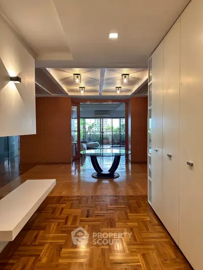 Spacious modern living area with elegant parquet flooring and stylish ceiling lights.