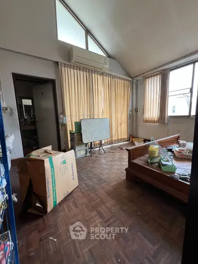Spacious room with parquet flooring and large windows, ideal for renovation.
