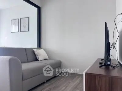 Modern living room with sleek gray sofa and wall-mounted TV, perfect for cozy relaxation.