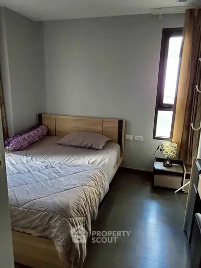 Cozy bedroom with modern decor and natural light from a large window.