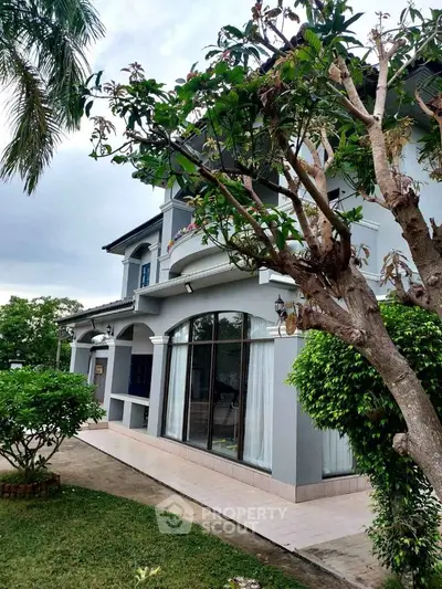 Elegant two-story house with lush garden and large windows