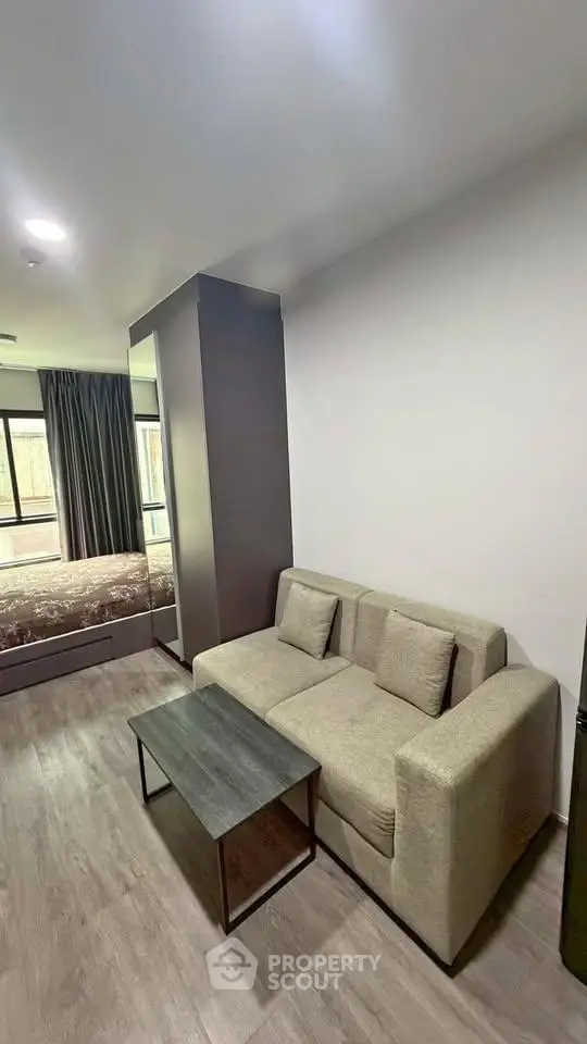 Modern studio apartment with cozy living area and bedroom, featuring sleek furniture and large windows.