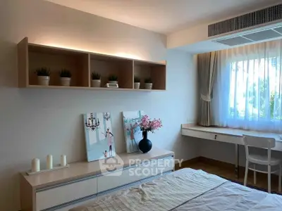 Charming bedroom with elegant decor and natural light, featuring a cozy workspace and stylish shelving.