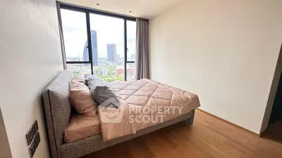 Modern bedroom with city view, featuring a cozy bed and large windows for natural light.
