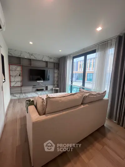Modern living room with stylish decor and large windows offering natural light.