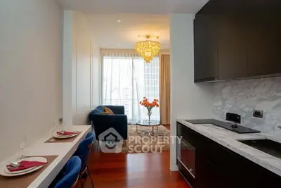 Modern open-plan kitchen and living room with elegant chandelier and city view.
