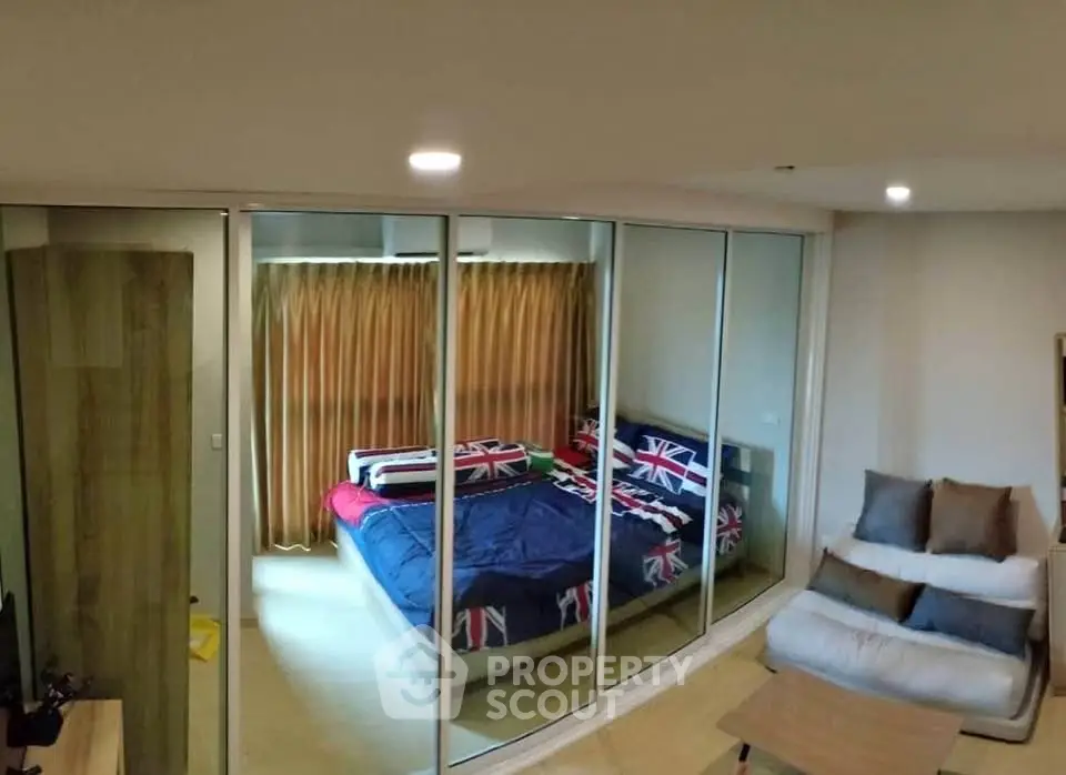 Modern bedroom with glass partition and cozy seating area, featuring stylish decor and ample natural light.