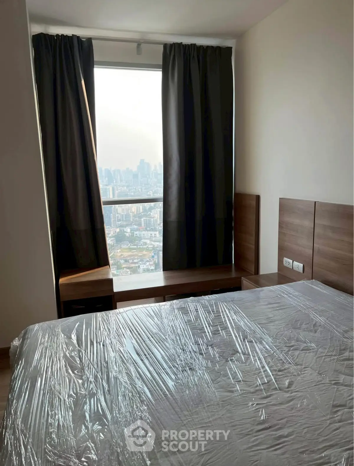 Modern bedroom with city view, featuring large window and sleek furniture, ideal for urban living.