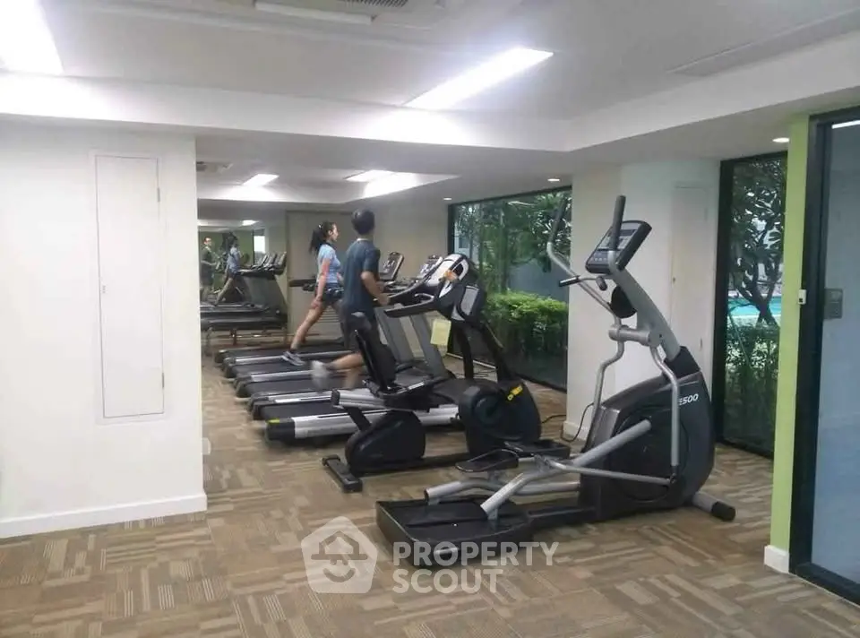 Modern gym with state-of-the-art equipment and large windows overlooking greenery.
