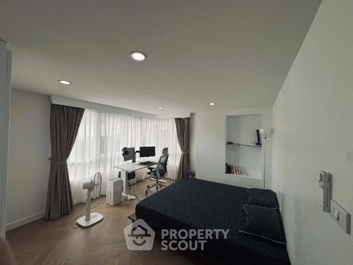 Spacious bedroom with study area and large windows in modern apartment