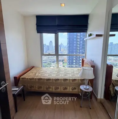 Cozy bedroom with city view, featuring a single bed, wooden flooring, and large window for natural light.