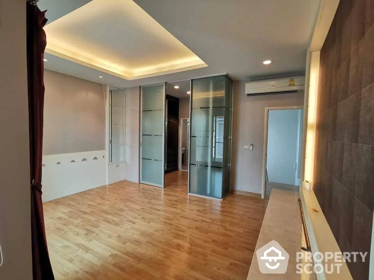 Spacious and modern living room with elegant wooden flooring, recessed lighting, and built-in storage, perfect for urban living.