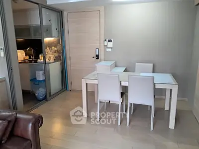 Modern dining area with sleek furniture and adjacent kitchen in open layout apartment.