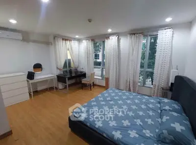 Spacious bedroom with modern decor and large windows offering natural light.