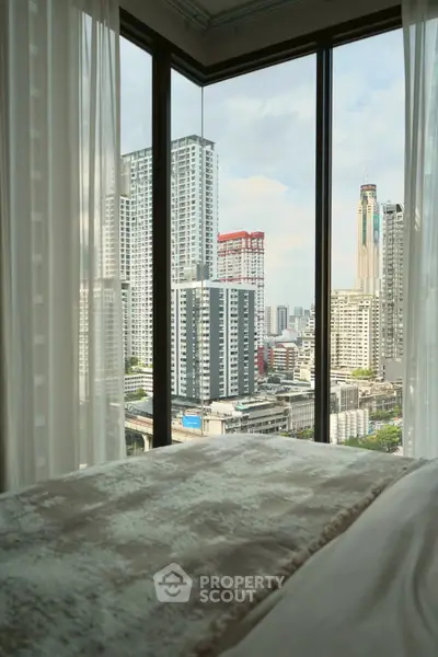Luxurious bedroom with stunning city view from floor-to-ceiling windows in high-rise apartment.