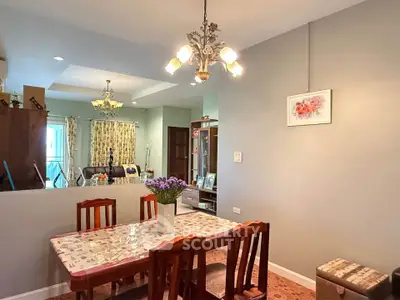 Charming dining area with elegant chandelier and cozy seating in a well-lit home interior.