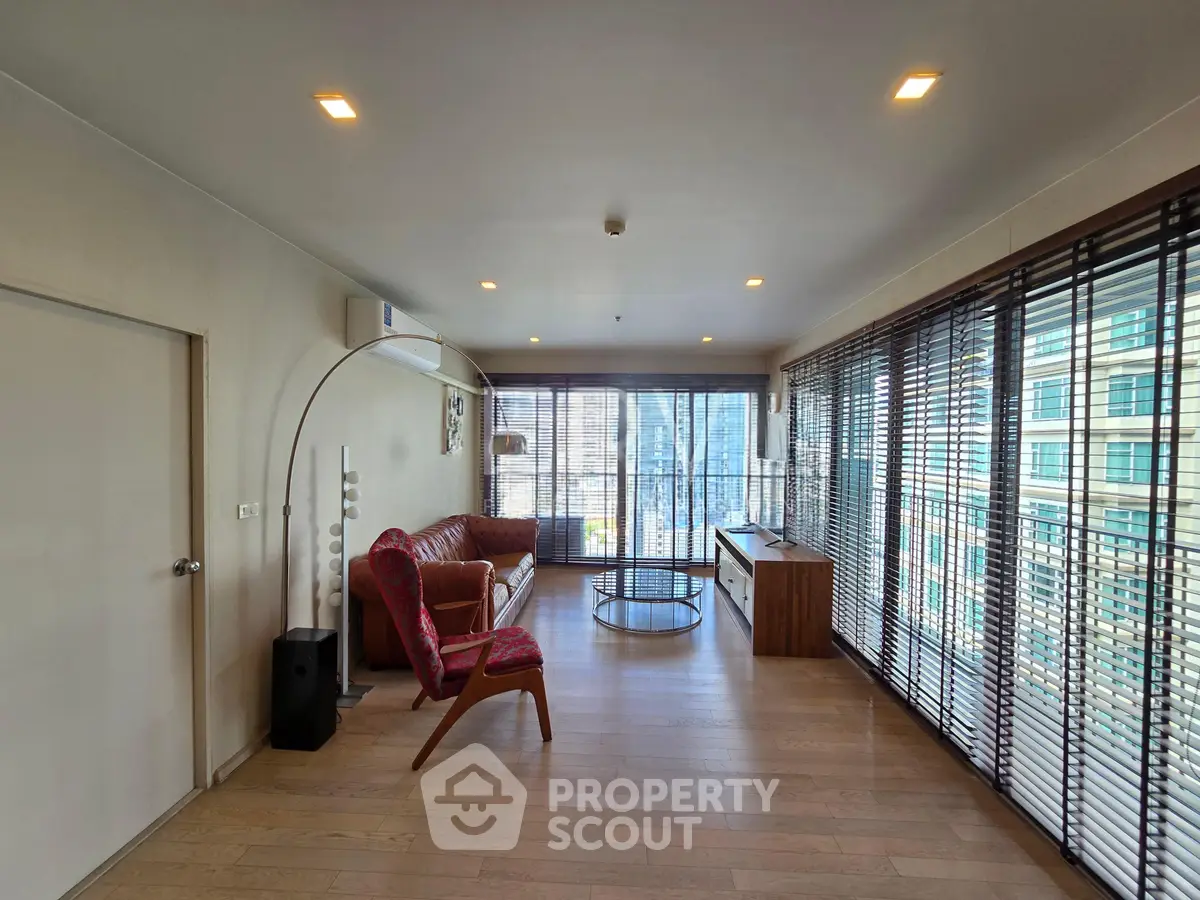 Spacious living room with modern furniture and large windows offering city views.