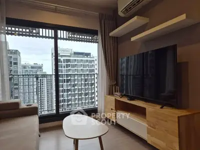 Modern living room with large TV and city view from balcony in high-rise apartment.