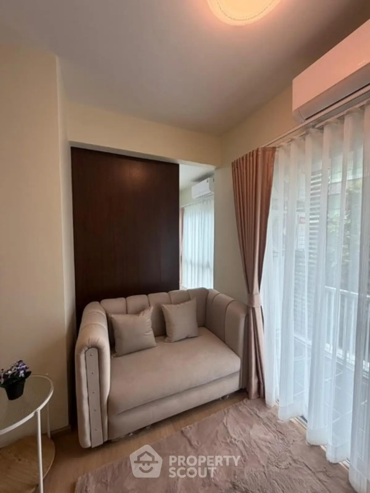 Cozy living room with plush sofa and large window, perfect for relaxation.