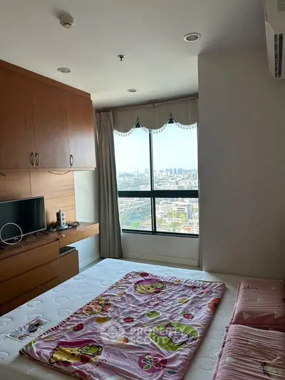 Cozy bedroom with city view, featuring built-in storage and a wall-mounted TV, perfect for urban living.