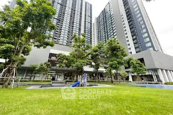 Modern high-rise building with lush green garden and playground