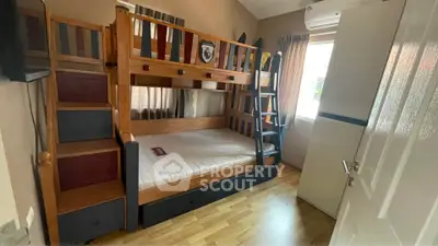 Charming bedroom with wooden bunk bed and natural light, perfect for kids.