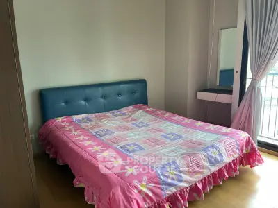 Cozy bedroom with colorful bedding and balcony access in modern apartment.