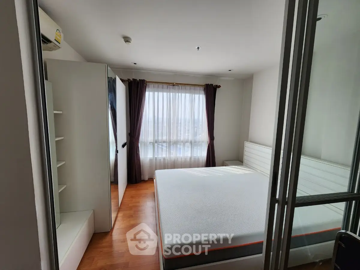 Spacious bedroom with large window and modern furnishings in a bright apartment.