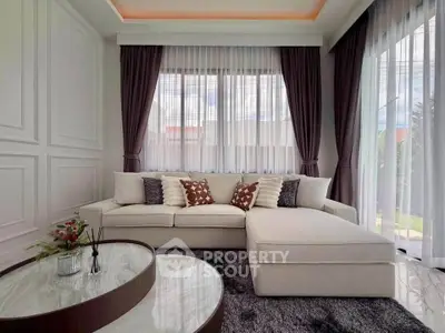 Elegant living room with modern sofa and stylish decor, featuring large windows and chic curtains.