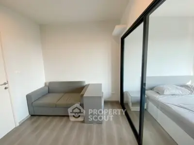 Modern bedroom with sleek mirrored wardrobe and cozy gray sofa