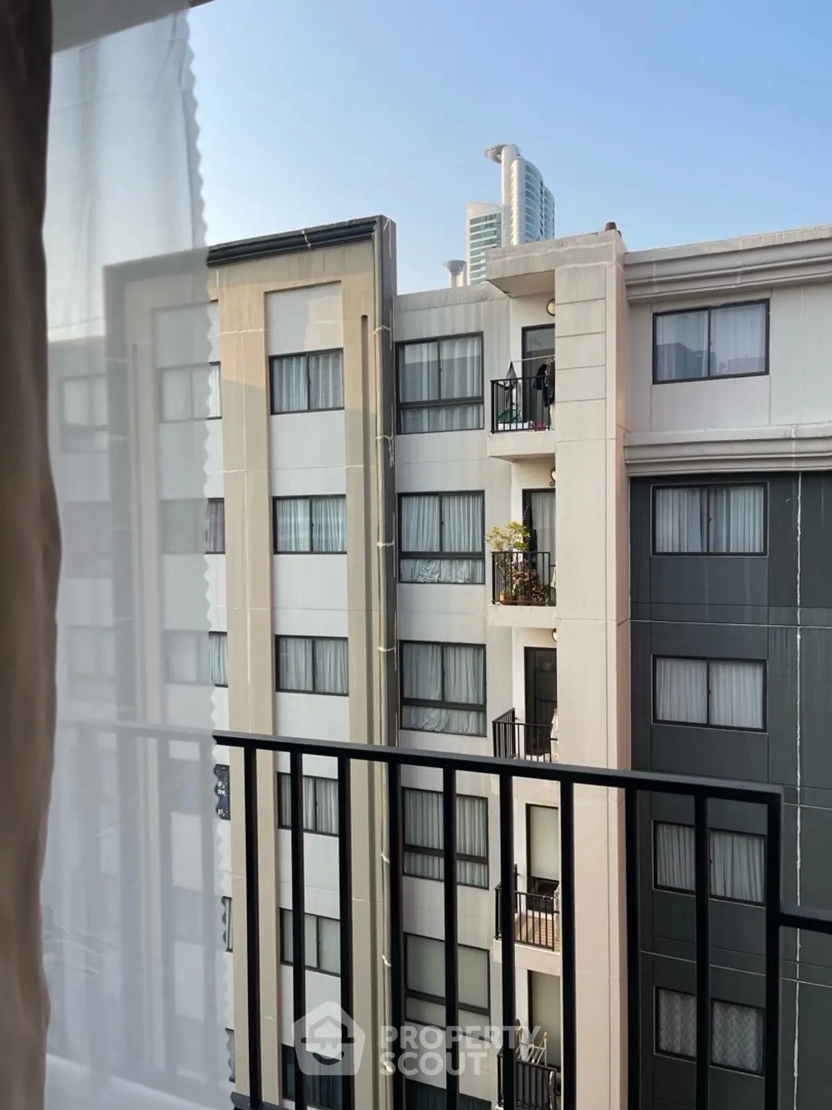 Urban apartment building view from balcony with modern architecture and city skyline.