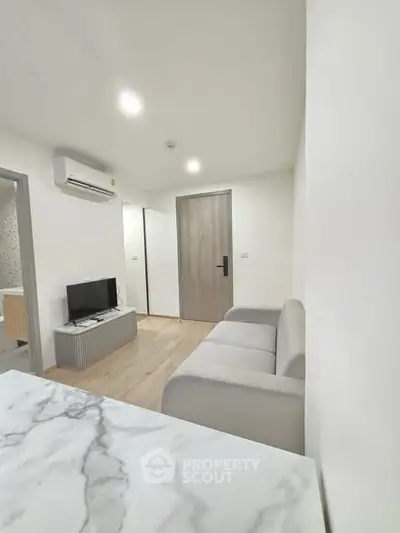 Modern living room with sleek design, featuring a cozy sofa and wall-mounted TV, perfect for relaxation.