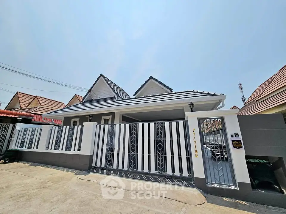 Charming single-story house with modern fence and driveway in a suburban neighborhood.
