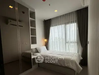 Cozy bedroom with large window and modern furnishings, perfect for urban living.