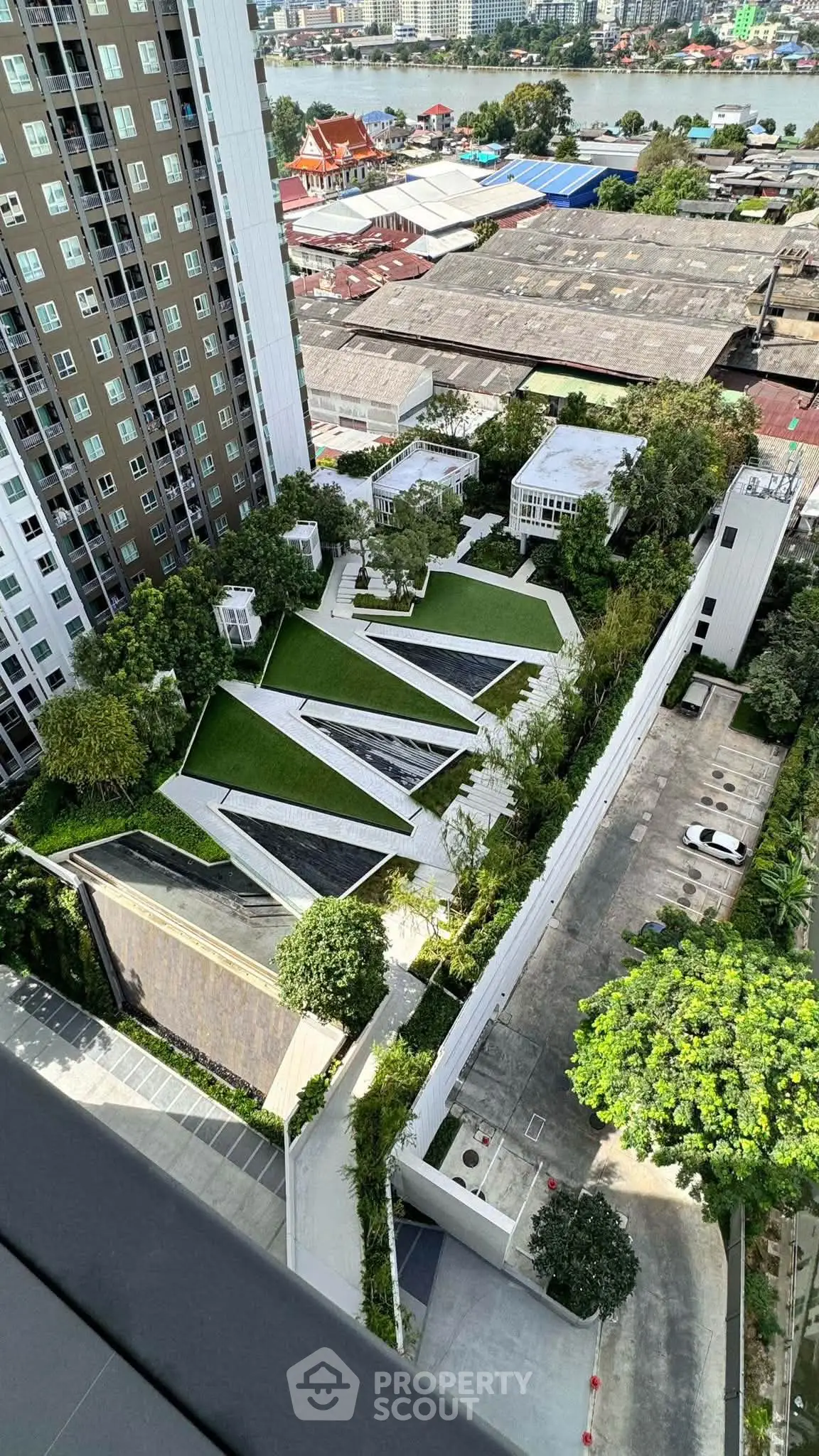 Stunning aerial view of modern residential complex with lush green gardens and cityscape backdrop.