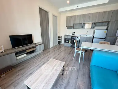 Modern open-layout living room with kitchen, featuring sleek furniture and appliances.