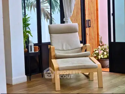 Stylish modern living room with cozy armchair and lush plants, perfect for relaxation.