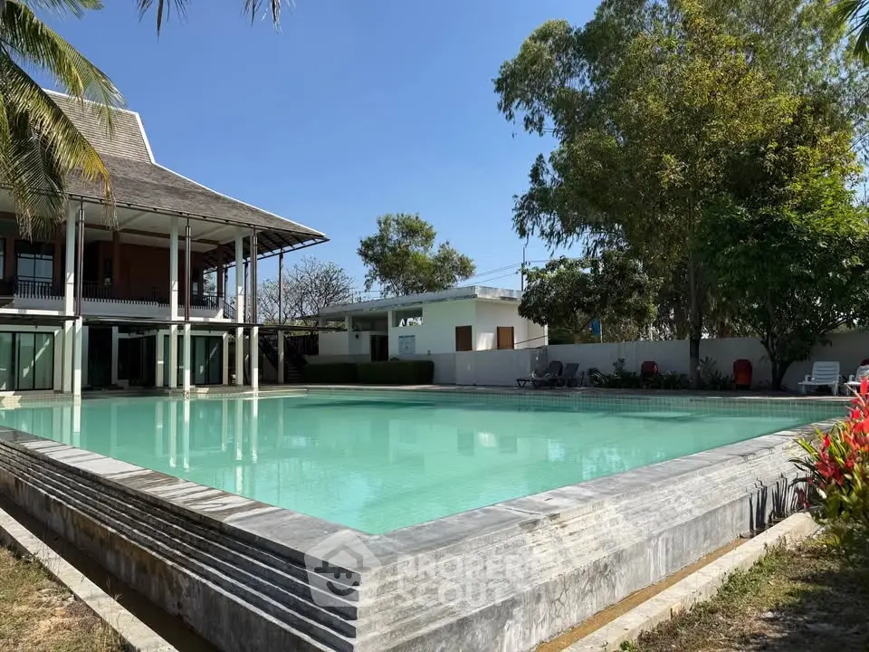 Luxurious property with a stunning pool and lush greenery, perfect for relaxation and entertainment.