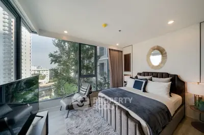 Luxurious bedroom with large windows and modern decor in high-rise building.