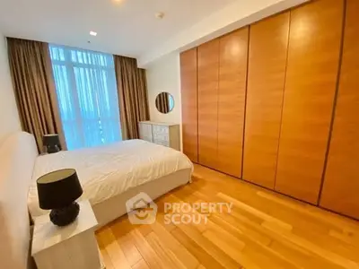 Spacious bedroom with wooden flooring and large wardrobe in modern apartment.
