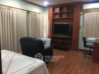 Cozy bedroom with wooden flooring, TV, and comfortable seating area for relaxation.