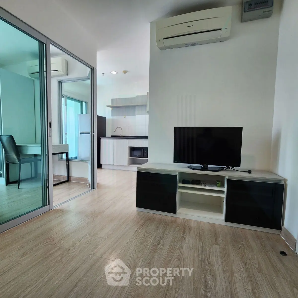 Modern living room with sleek TV stand, air conditioning, and open kitchen layout in stylish apartment.